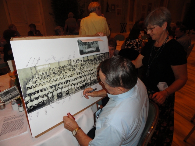 Sylvia Bly brought along an enlarged copy of the 1956 Boynton 8th Grade picture for everyone to sign. Here, Tom Vormwald adds his signature.